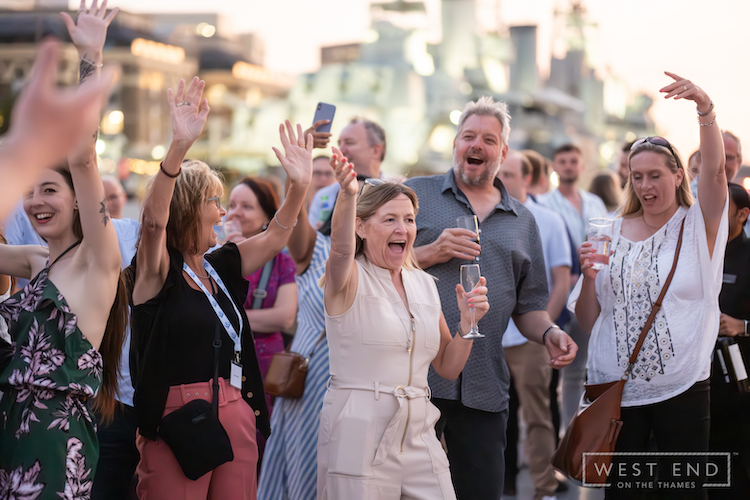 a happy corporate group on the outdoor deck on the Thames with West End on the Thames