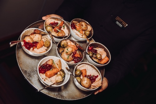 Server holding a tray of seasonal winter bowl food dishes during a corporate event on the Thames