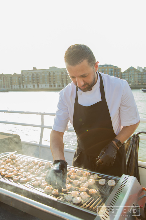 Guests enjoying the "theatre" of live cooking on the deck, featuring our 2026 summer BBQ menu.