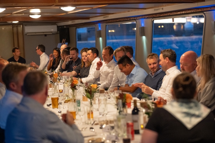 Indoor banquet setup in the vessel saloon featuring long dining tables, professional guest layout, and panoramic windows facing the River Thames.